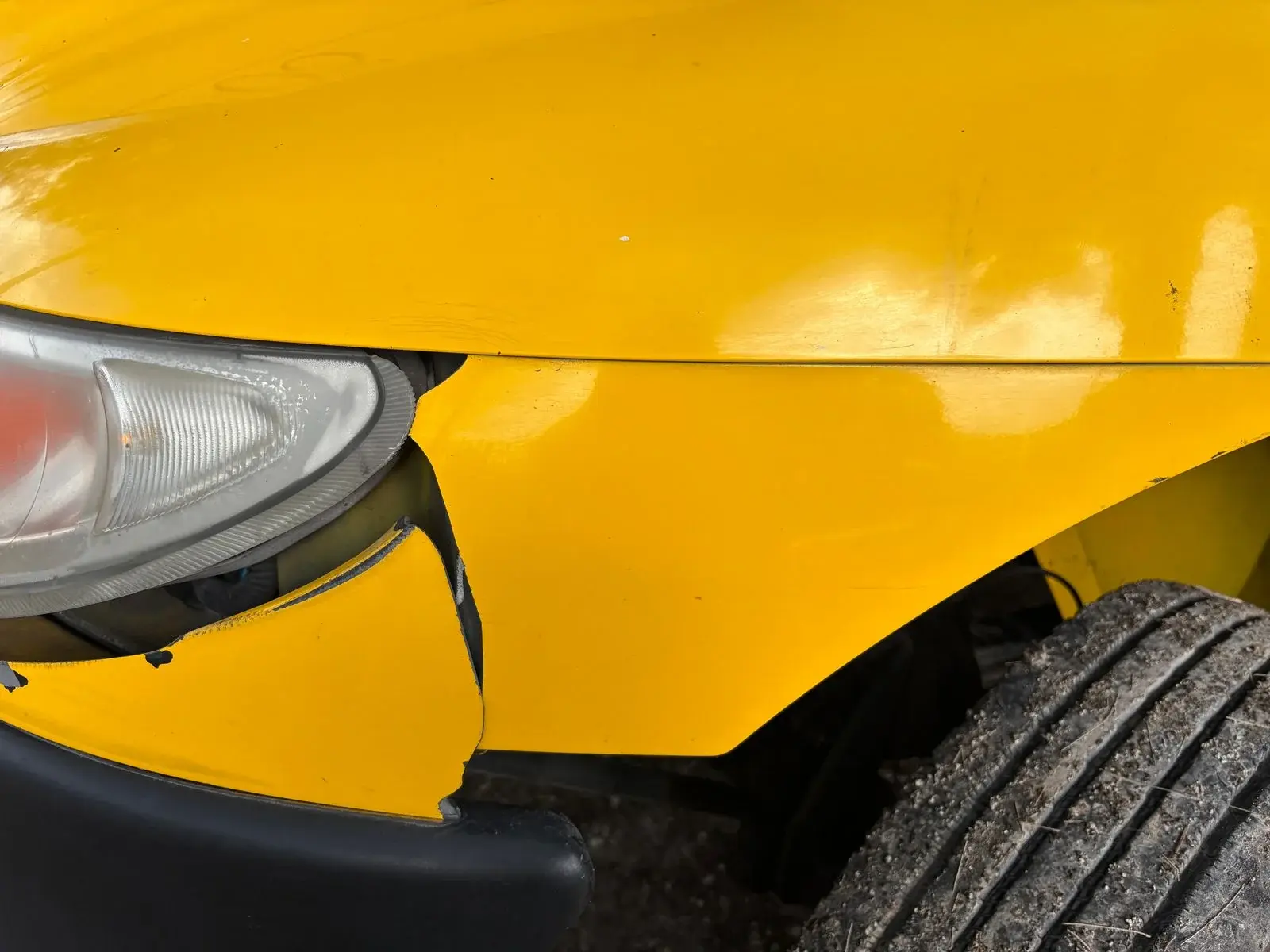 Cracked yellow bumper separating from the adjacent body panel